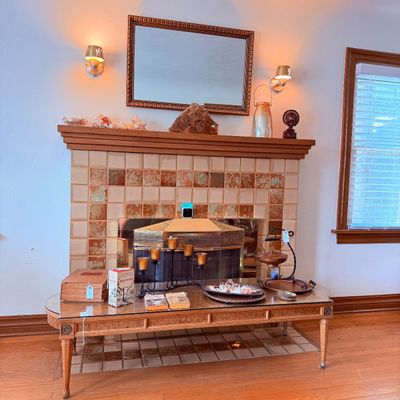 Sale Photo Thumbnail #19: A light wood coffee table with a glass top, decorative home goods. Items include a wrought iron candelabra, vintage books, a wooden box, and decorative trays.