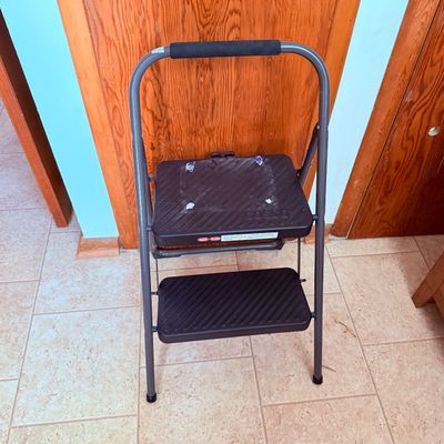 Sale Photo Thumbnail #85: Cosco two-step folding ladder with a gray metal frame and black treads.