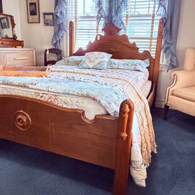 Sale Photo Thumbnail #32: Vintage carved wooden four-poster bed frame with a scalloped headboard and footboard, dressed in a floral quilt and accent pillows.