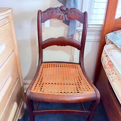 Sale Photo Thumbnail #38: Antique wooden side chair featuring a carved rose crest and a woven cane seat.