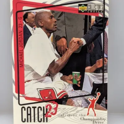 Sale Photo Thumbnail #806: 1997-98 Upper Deck Collector's Choice Michael Jordan "Catch 23" trading card #23G, featuring Jordan on the bench during the Championship Drive series.