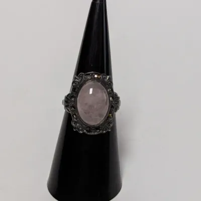 Sale Photo Thumbnail #965: Vintage sterling silver ring featuring a central oval cabochon rose quartz surrounded by a marcasite halo.