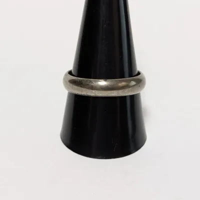 Sale Photo Thumbnail #960: Simple sterling silver or white metal ring displayed on a black ring cone, featuring light tarnishing and wear.