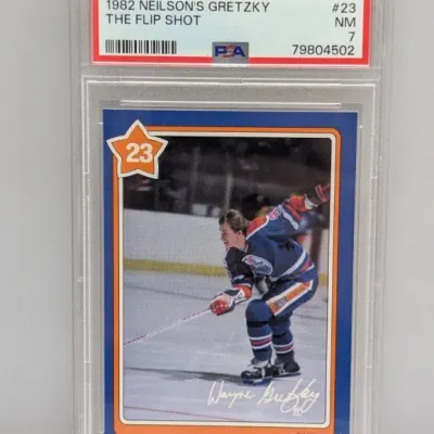 Sale Photo Thumbnail #33: PSA-graded 7 NM 1982 Neilson's Gretzky "The Flip Shot" #23 hockey trading card encapsulated in a protective slab.