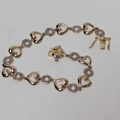 Sale Photo Thumbnail #975: Gold-tone tennis-style link bracelet featuring openwork heart and pave-set round accents with a box clasp and safety latches.