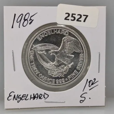 Sale Photo Thumbnail #1018: 1985 Engelhard one troy ounce .999 fine silver round featuring an American eagle design, housed in a cardboard flip holder.