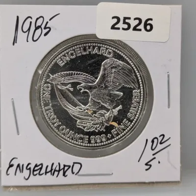 Sale Photo Thumbnail #1017: 1985 Engelhard Prospector 1 troy ounce .999 fine silver round featuring an American eagle design, housed in a cardboard flip holder.
