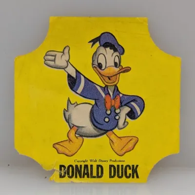 Sale Photo Thumbnail #181: Vintage yellow paper or cardboard Donald Duck die-cut insert featuring Walt Disney Productions copyright, showing edge wear and slight tears at the bottom.