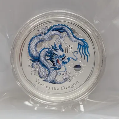 Sale Photo Thumbnail #1000: Perth Mint Year of the Dragon silver coin featuring a blue colored Chinese dragon design, encapsulated in a protective plastic casing.