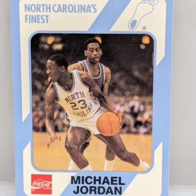 Sale Photo Thumbnail #601: 1985-86 Collegiate Collection Michael Jordan basketball card, featuring his North Carolina Tar Heels era and Coca-Cola branding.