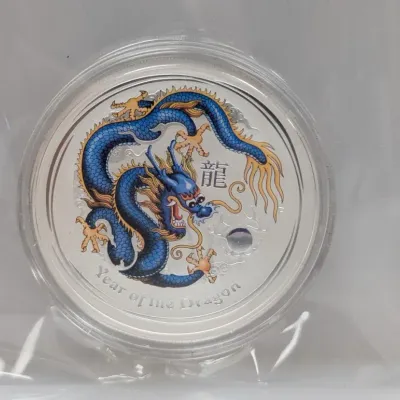 Sale Photo Thumbnail #995: Perth Mint Year of the Dragon colorized silver coin in a clear protective plastic capsule and sleeve.