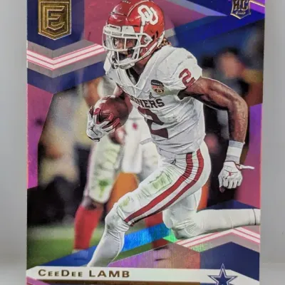 Sale Photo Thumbnail #530: 2020 Panini Elite CeeDee Lamb rookie card featuring a pink and purple geometric foil parallel design. The card depicts Lamb in his Oklahoma Sooners uniform with a Dallas Cowboys logo branding.