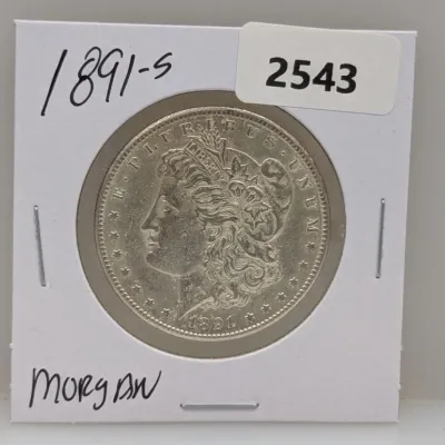 Sale Photo Thumbnail #1034: 1891-S Morgan silver dollar coin housed in a protective cardboard flip holder.