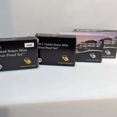 Sale Photo Thumbnail #1065: Four boxed United States Mint Silver Proof Sets, including annual issues from 2011, 2012, 2014, and 2015, all in original US Mint packaging.