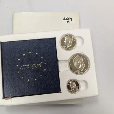 Sale Photo Thumbnail #1053: 1976 United States Bicentennial Silver Proof Set, including a quarter, half dollar, and dollar coin in original display case and outer box.