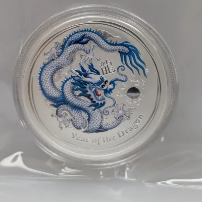Sale Photo Thumbnail #996: Perth Mint Year of the Dragon silver coin with blue colorized detail, housed in a protective plastic capsule and sleeve.