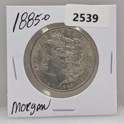 Sale Photo Thumbnail #1030: 1885-O Morgan silver dollar coin housed in a protective cardboard flip.