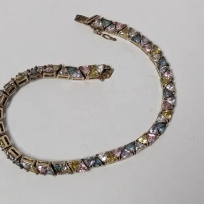 Sale Photo Thumbnail #971: Sterling silver tennis bracelet set with triangular multi-color cubic zirconia or synthetic gemstones, featuring a box clasp with safety latch.