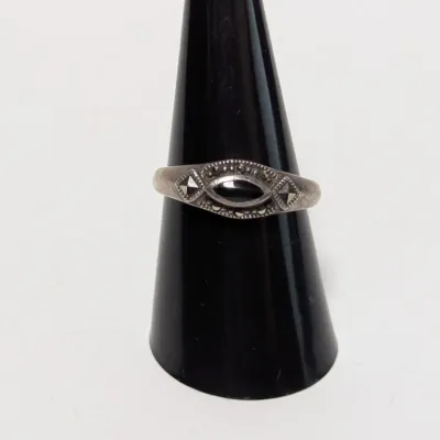 Sale Photo Thumbnail #961: Vintage sterling silver ring featuring a central marquise-cut onyx surrounded by marcasite accents on a black display cone.
