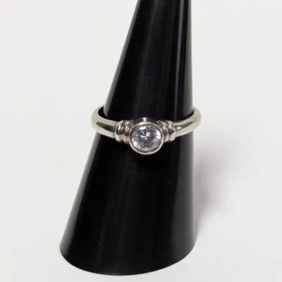 Sale Photo Thumbnail #967: Sterling silver or white gold ring featuring a bezel-set round solitaire stone with ribbed shoulders, displayed on a black ring cone.