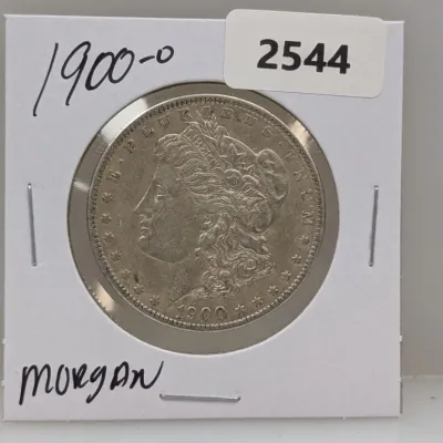 Sale Photo Thumbnail #1035: 1900-O Morgan silver dollar coin, housed in a cardboard flip labeled with item details.