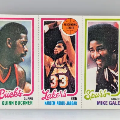 Sale Photo Thumbnail #172: 1980-81 Topps basketball three-panel card featuring Quinn Buckner, Kareem Abdul-Jabbar, and Mike Gale, appearing in good vintage condition with clean borders.