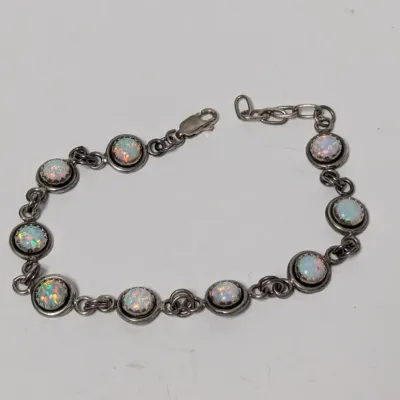 Sale Photo Thumbnail #968: Sterling silver link bracelet featuring circular bezel-set synthetic or natural opal cabochons with iridescent color play, finished with a lobster claw clasp.