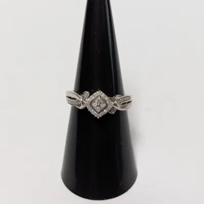 Sale Photo Thumbnail #946: Sterling silver or white gold diamond cluster ring with a square-shaped central setting and pave accents on the split shank, presented on a black cone display.