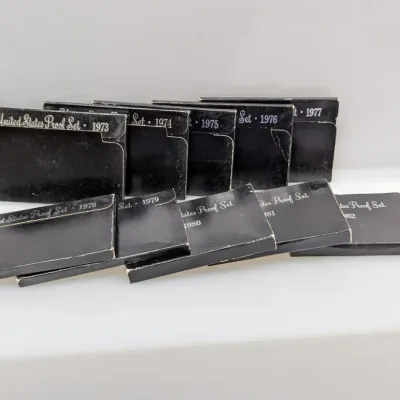 Sale Photo Thumbnail #1059: Collection of United States Proof Sets from 1973 through 1982 in original black packaging.