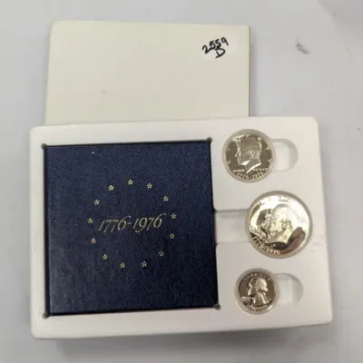 Sale Photo Thumbnail #1054: 1976 United States Bicentennial Silver Proof Set, featuring a quarter, half dollar, and dollar coin in original presentation packaging.