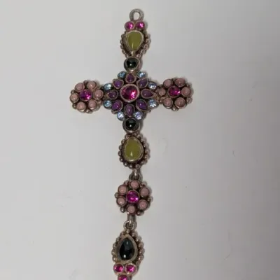Sale Photo Thumbnail #990: Ornate silver-tone cross pendant embellished with multicolored rhinestones and cabochons in shades of pink, purple, blue, green, and black.