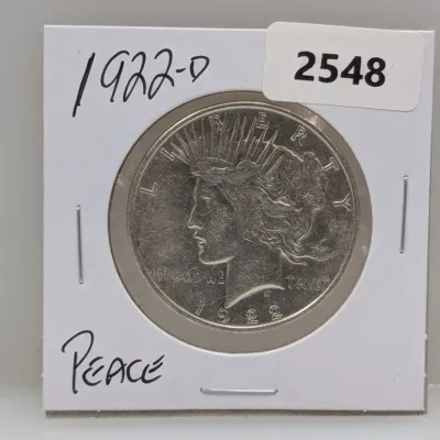 Sale Photo Thumbnail #1039: 1922-D Peace silver dollar coin in a protective cardboard flip holder.