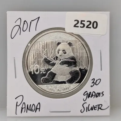 Sale Photo Thumbnail #1011: 2017 Chinese Silver Panda 10 Yuan coin, featuring a giant panda holding bamboo and containing 30 grams of .999 fine silver, presented in a cardboard coin flip.