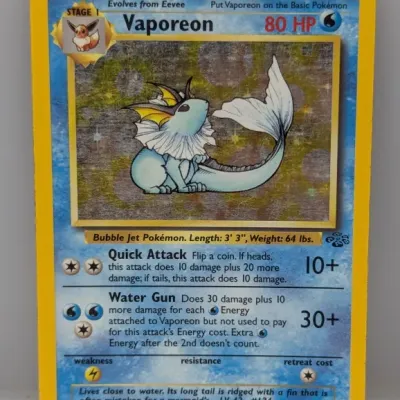 Sale Photo Thumbnail #202: Vintage Vaporeon 12/64 holographic Pokémon card from the 1999 Jungle set. The card shows light edge wear and surface scratching on the foil illustration.
