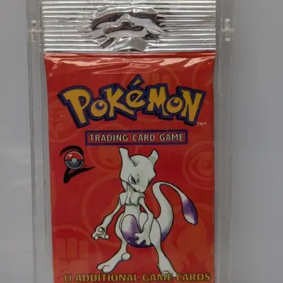 Sale Photo Thumbnail #42: Sealed Pokémon Base Set 2 booster pack featuring Mewtwo artwork, housed in a hard plastic protective case.