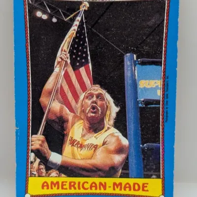 Sale Photo Thumbnail #261: Vintage Hulk Hogan WWF wrestling card titled "American-Made" featuring a blue border and rope frame, circa 1980s.