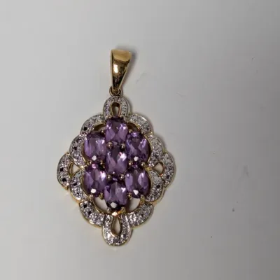 Sale Photo Thumbnail #980: Gold-tone pendant featuring a cluster of marquise-cut purple stones surrounded by an openwork halo set with clear accent stones.