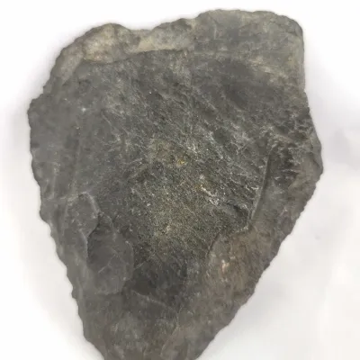Hand-carved dark gray stone arrowhead artifact featuring visible knapping edges.