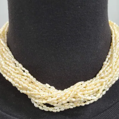 Multi-strand freshwater rice pearl necklace in a classic twisted torsade design, displayed on a black jewelry bust mannequin.