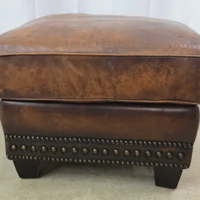 Rustic distressed brown leather ottoman with nailhead trim and dark wood tapered block feet.