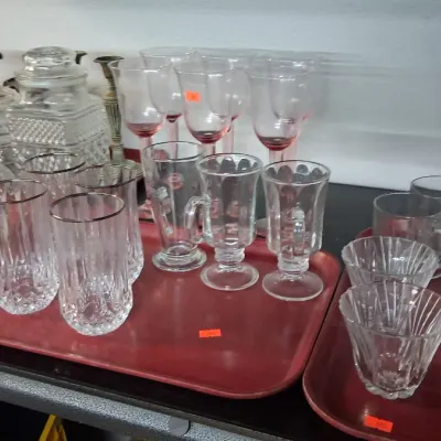 Collection of vintage glassware, including crystal highball glasses with silver rims, footed Irish coffee mugs, wine glasses with pink...