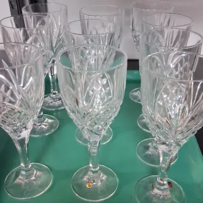 Set of cut crystal wine goblets with crisscross and fan detailing, arranged on a green plastic tray.