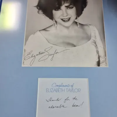 Framed autographed black-and-white portrait of Elizabeth Taylor, featuring a printed signature on the photo and a handwritten thank-you...