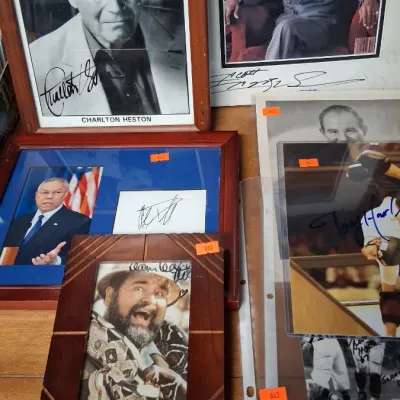 Collection of framed and unframed autographed photos and memorabilia, featuring Charlton Heston, Sugar Ray Leonard, Colin Powell, and Dom...