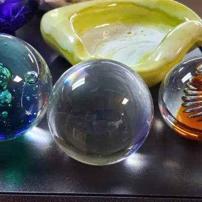 Collection of decorative art glass items, featuring three paperweights with bubble and swirl interior details alongside a yellow freeform...