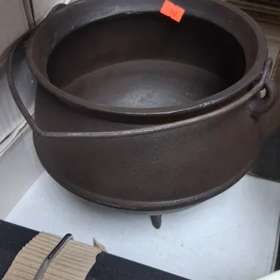Vintage cast iron three-legged kettle cauldron with a metal wire bail handle.
