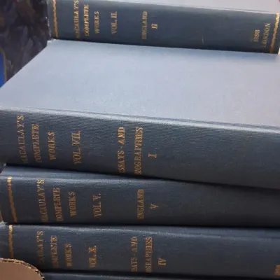 Stack of hardbound books, "Macaulay's Complete Works," featuring dark blue covers with gold gilt lettering on the spines.