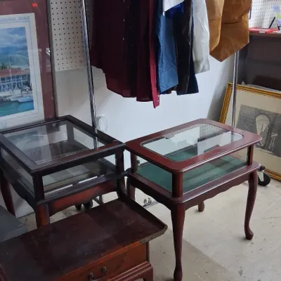 Collection of traditional dark wood furniture pieces, including two glass-top display side tables and a low single-drawer chest, shown...