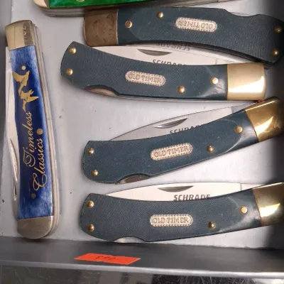 Collection of pocket knives including Schrade Old Timer models and Timeless Classics folding knives in a storage tray.
