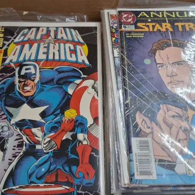 Cardboard box containing bagged and boarded vintage comic books, including Marvel Comics Captain America #425 and DC Star Trek Annual #5.